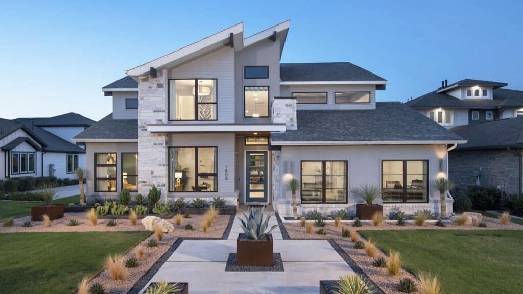 Modern two-story new construction home with stone accents and landscaped front yard at dusk.
