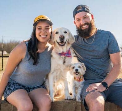 A smiling couple with their dogs between them