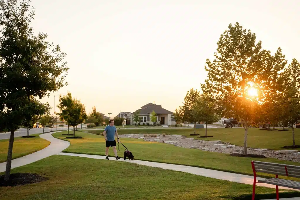 Man walking dog in park at Easton Park, Austin, Texas.